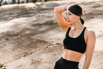 Portrait of a wonderful young woman athlete in black fitness attire outdoors