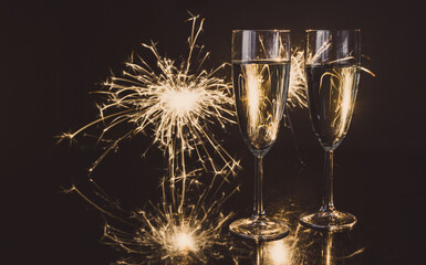 Two glasses of champagne with sparklers in background. New Year's Eve celebration party.