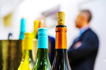 Bottles of wine on the background of the bartender. Tasting and trade in alcoholic beverages. Selective focus. Unrecognizable faces