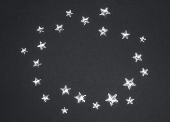 Beautiful shining silver stars with embossed transparent top arranged in circle on trendy grey background. Color 2021 concept. Copy space. Top view.