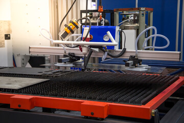 Mechanical vacuum lifter loading metal sheet to laser cutting machine in production line. Industrial metalworking machinery