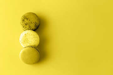 Three macaroons in stack toned in trendy yellow. Trendy background for your design. Color 2021 concept. Food concept in vintage style. Copy space. Flat lay style.
