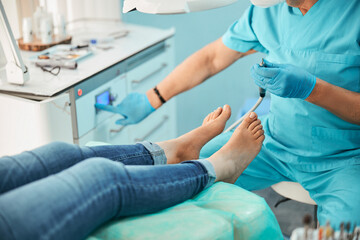 Female patient in the process of hardware skin treatment procedure by foot