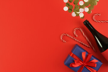 champagne christmas bottle and decoration with confetti on red background. Concept holiday atmosphere, new year, celebration, greeting card. Flatlay, top view, frame, copyspace
