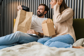 Couple eating take-away food in bedroom