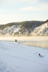 Landscape of snowy mountains and foggy rivers. Winter fishing.