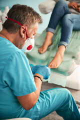 Pedicurist doctor in medical mask doing peeling by patient feet