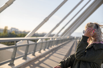 Mujer de negocios viajando con maleta en un puente exterior gafas de sol rubia con chaqueta invierno