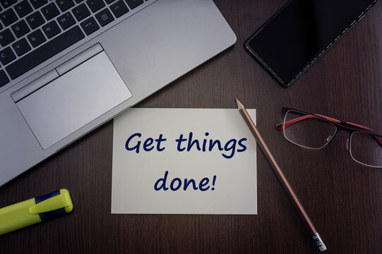 Get things done card. Top view of office table desktop background with laptop, phone, glasses and pencil with card with inscription get things done.  Business concept.