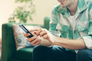 Young man on a couch at home, using mobile phone