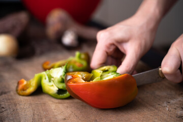 man cutting bell pepper a wooden board
