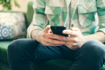 Young man on a couch at home, using mobile phone