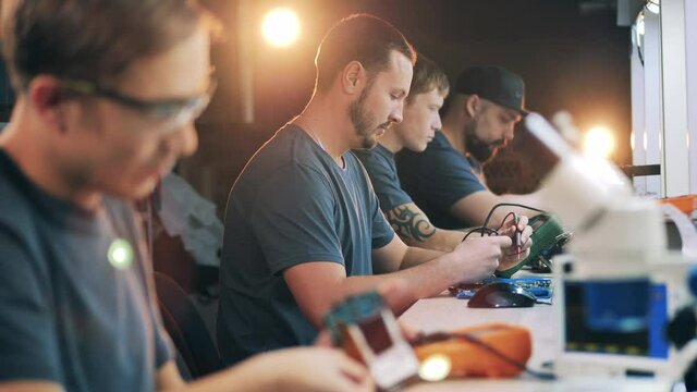 Male engineers are fixing and soldering gadgets