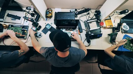 Top view of servicemen fixing laptops and microcircuits