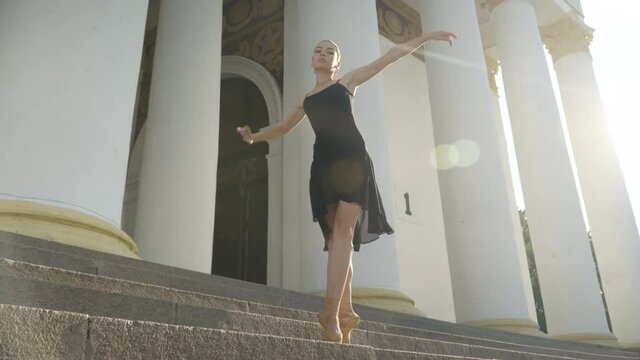 Wide shot portrait of slim young woman dancing on tiptoes in sunrays outdoors. Confident elegant slender Caucasian ballerina dance in sunlight. Choreography and femininity.