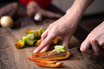 man cutting bell pepper a wooden board

