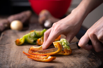 man cutting bell pepper a wooden board
