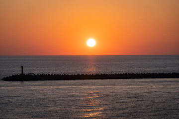 Sunset in Black Sea. Sun illuminates sea surface. Sky over sea in orange. Sun sets in sea. Winter evening in Sochi. Atmosphere of rest and relaxation.
