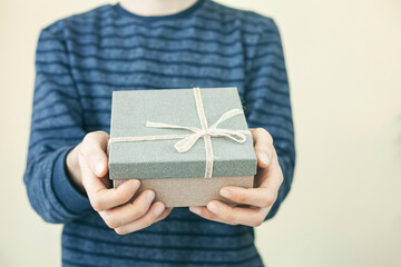 Close up shot of female hands holding a small gift wrapped with pink ribbon