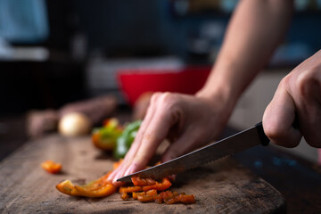 man cutting bell pepper a wooden board
