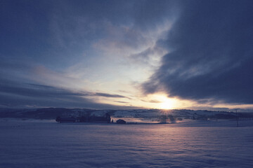 sunset over the farm and the fields in winter