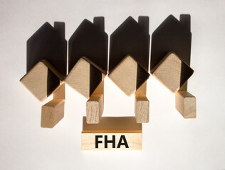 FHA symbol. Houses created by shadows from cubes. The word 'FHA - federal housing administration' on a wooden block. Beautiful white background, copy space. Business and FHA concept.