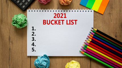 Fototapeta na wymiar 2021 bucket list symbol. White note with inscription '2021 bucket list' on beautiful wooden table, colored paper, colored pencils, clips, coins and calculator. Business and 2021 bucket list concept.