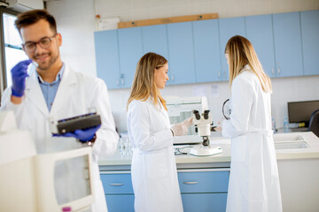 Fototapeta premium Researcher in protective workwear standing in the laboratory and analyzing liquid samples