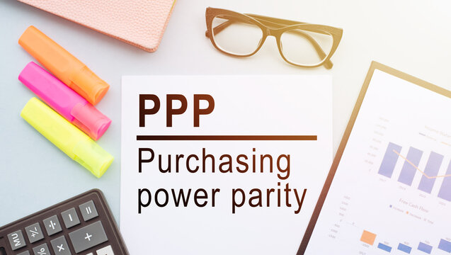 The text PPP PURCHASING POWER PARITY on office desk with calculator, markers, glasses and financial charts.