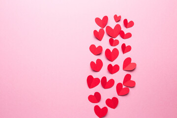 A lot of small hearts of red color against on a pink background. Happy Valentine's Day.