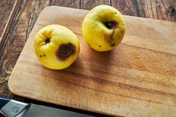 Two wrinkled and rotten apples on a cutting board. Improper storage, damage to fruit.
