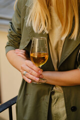 Beautiful girl with a wine glass on the balcony. Drinks white wine and enjoy the moment. A celebration holiday alone. Relaxed lifestyle. Happy woman rest after work. Beautiful European courtyard