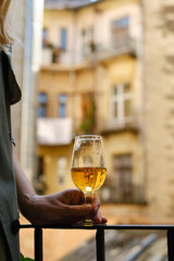 Beautiful girl with a wine glass on the balcony. Drinks white wine and enjoy the moment. A celebration holiday alone. Relaxed lifestyle. Happy woman rest after work. Beautiful European courtyard