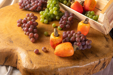 Grapes in a wooden box and cashews with fabrics in the background, low depth of field, selective focus.