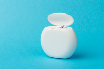 Dental floss container on blue background. Daily oral hygiene, teeth care and health. Cleaning...