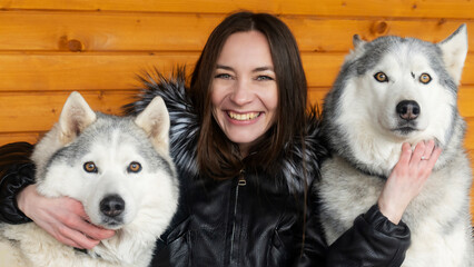 Portrait of caucasian white brunette women in black winter coat smiling next to a two grey husky dogs. Friendship concept. © kalyanby