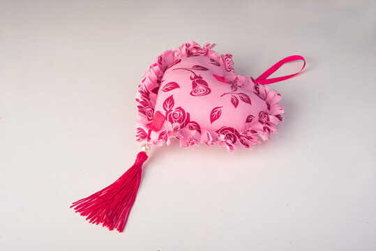 Pink heart on white surface, selective focus.