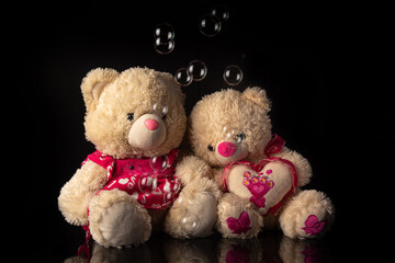 Teddy bears with soap bubbles on black background, selective focus.