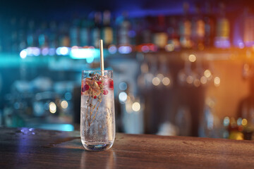 modern gin tonic cocktail with ice, straw and red berries on bar counter - obrazy, fototapety, plakaty