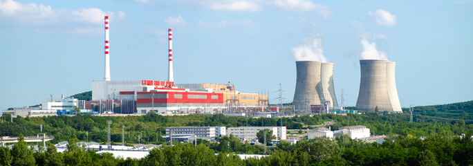 Panoramic view on nuclear power plant with steaming cooling towers on the background of blue sky 
