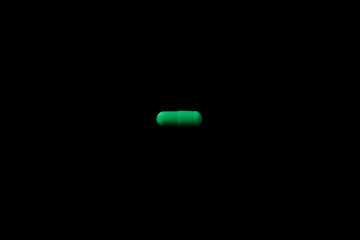 green pills capsule on black bakcground