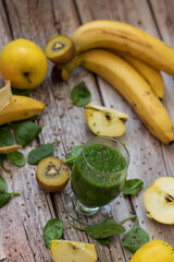 
A glass of kiwi, spinach and apple smoothie. Health drink. Apples, flax seeds, spinach, kiwi, bananas lie nearby.