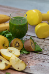 
A glass of kiwi, spinach and apple smoothie. Health drink. Apples, flax seeds, spinach, kiwi, bananas lie nearby.