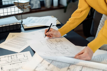 Woman working at office with blueprint and documents
