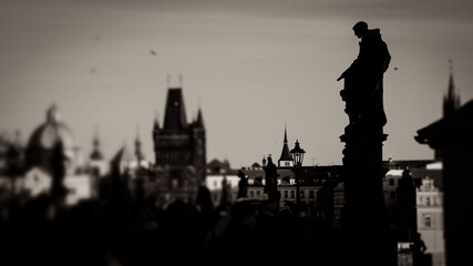 Fototapeta premium Künstlerisch gestaltete Schwarz-Weiß-Aufnahmen von Prag: Brückenfigur und Stadtsilhouette