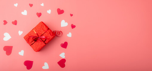 Valentine's day gift. Box in red packaging on a pink background with hearts. Banner. Place for your text.