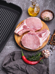 fresh raw pieces meat pork, beef, chop on a bone on the board, spices, grill pan