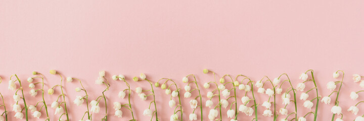 Header with frame made of lily of the valley flowers on a pink background. Spring tenderness concept with copy space.