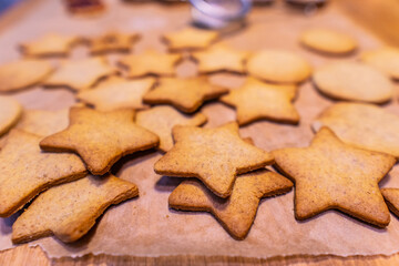 Homemade gingerbread cookies (stars) on baking paper and rustic wooden table