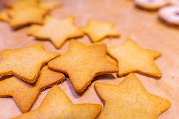 Homemade gingerbread cookies (stars) on baking paper and rustic wooden table
